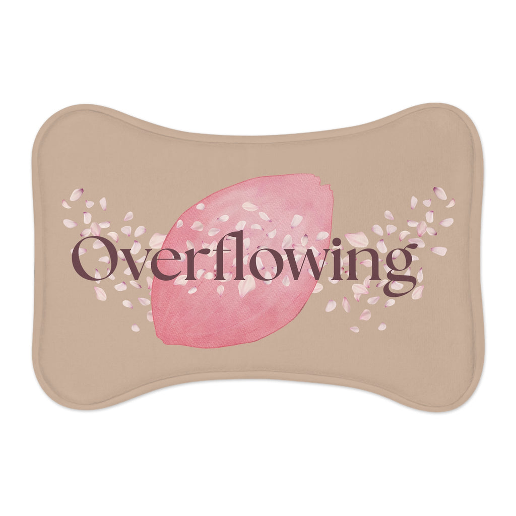 Front view of a tan pet feeding mat with the words, " Overflowing" on the front with a rose petal design