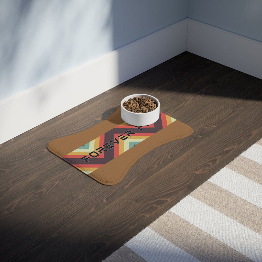 Pet feeding station with food and water bowls on caramel colored “Forever Fed” mat with retro stripes, placed on hardwood floor.