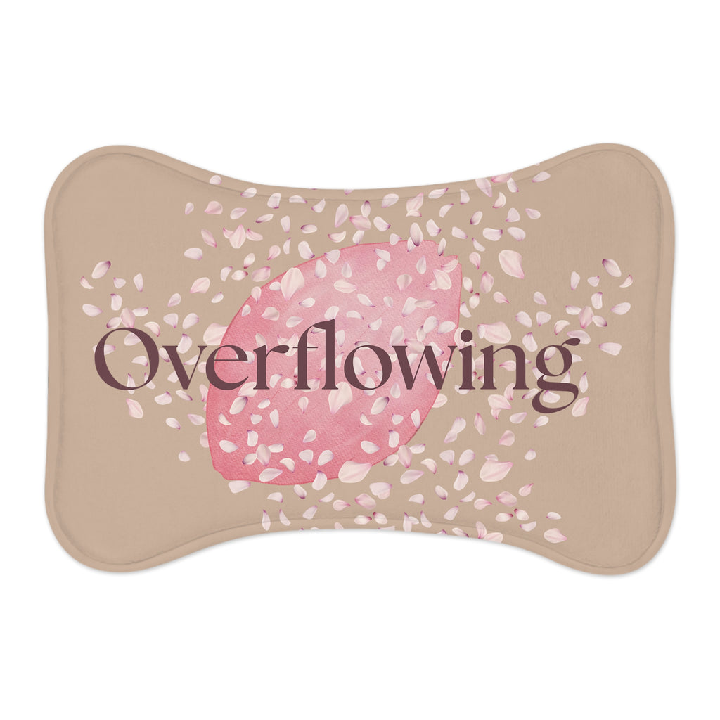 Beige pet feeding mat with pink petal design and the word “Overflowing” printed across the center – symbolizing faith, love, and abundance at mealtime.