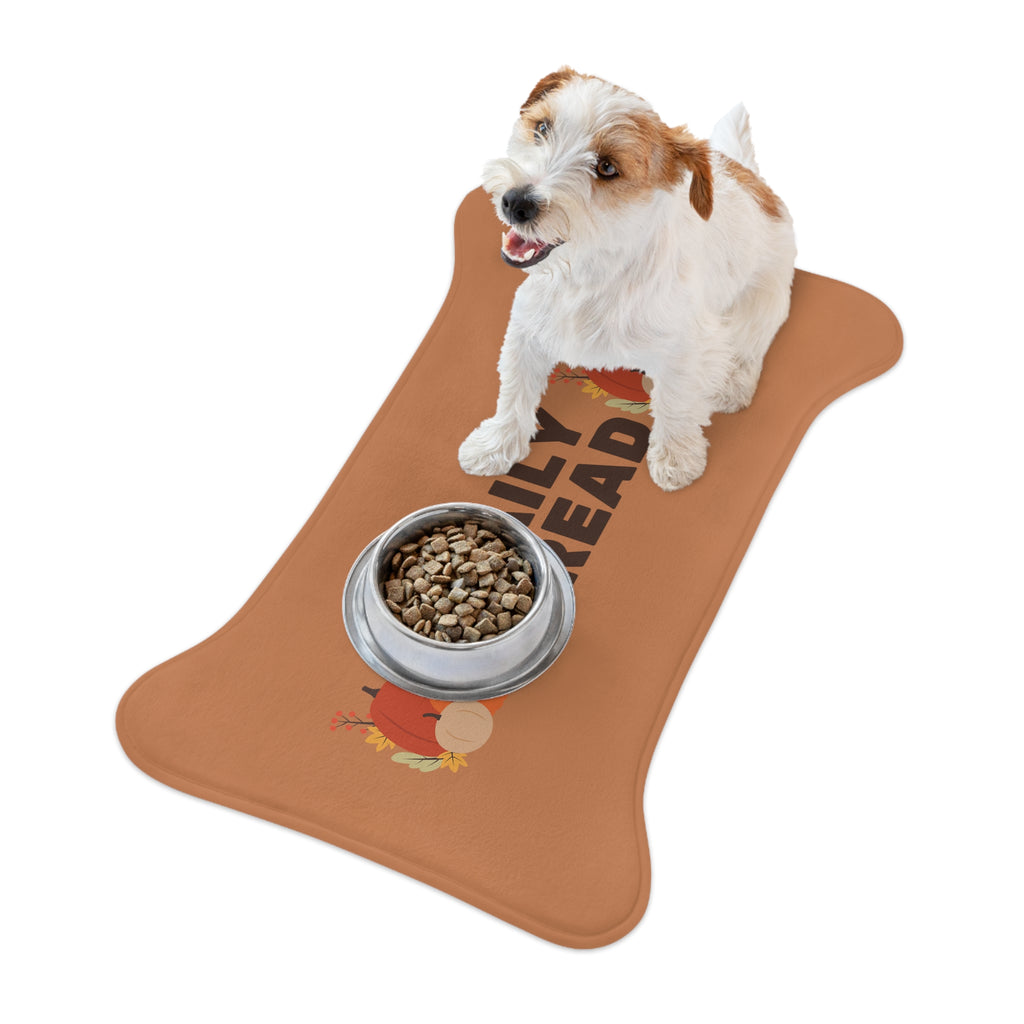 Brown and white dog sitting beside a white food bowl on a fall-themed pet feeding mat with pumpkin and leaf print