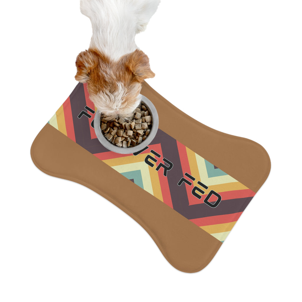 Brown and white dog eating kibble on “Forever Fed” retro-style pet feeding mat with food bowl.