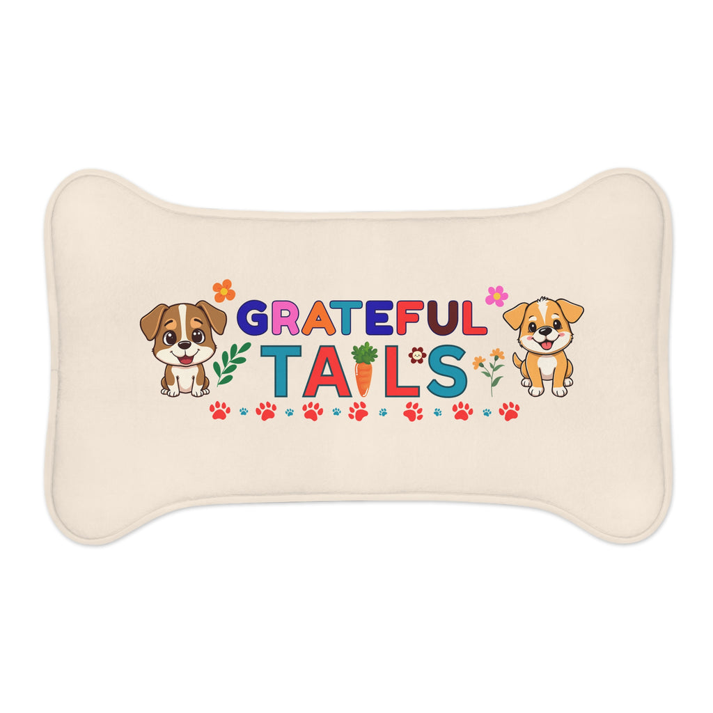 Bone-shaped cream pet feeding mat with “Grateful Tails” text, colorful letters, paw prints, flowers, carrot graphic, and two cartoon puppies.