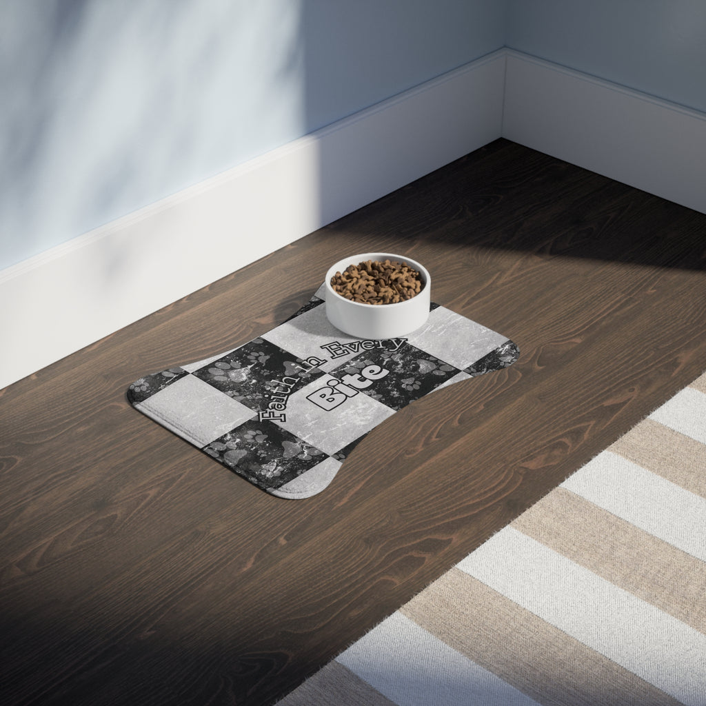 Bone‑shaped plush pet feeding mat in black and white checkerboard paw print design, featuring the phrase “Faith in Every Bite”.