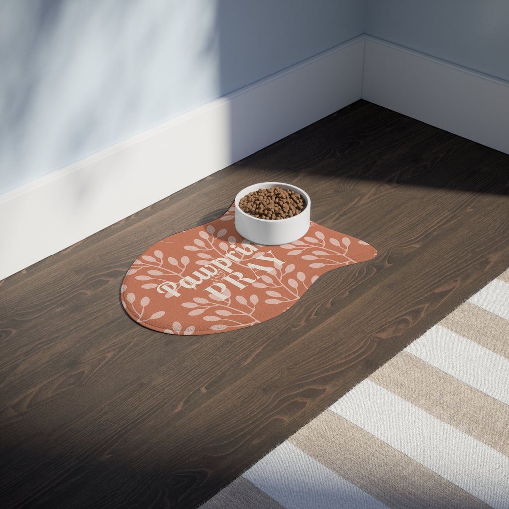 Terracotta fish-shaped pet feeding mat with white floral print and food bowl on dark wood floor near striped rug.