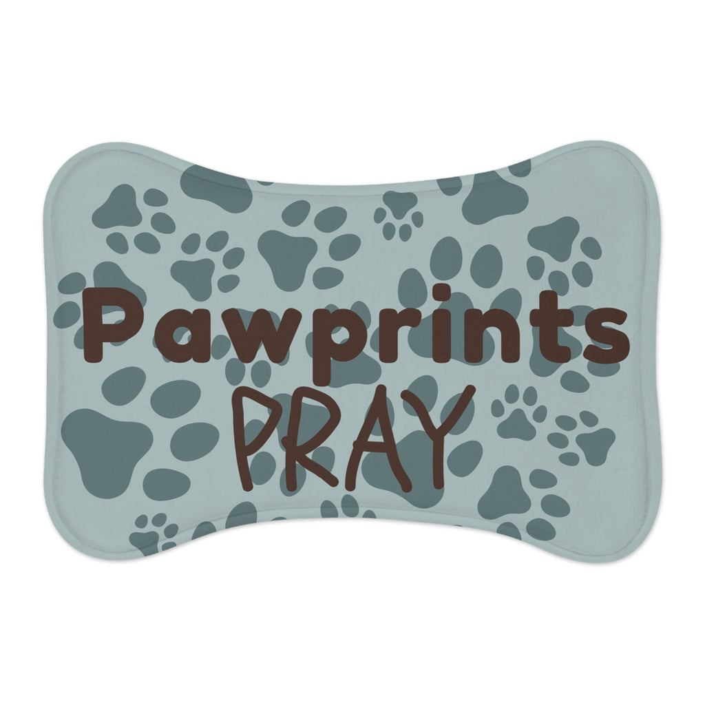 Bone‑shaped plush pet feeding mat with aqua background, dark grey paw print pattern, and brown text “Pawprints Pray”.