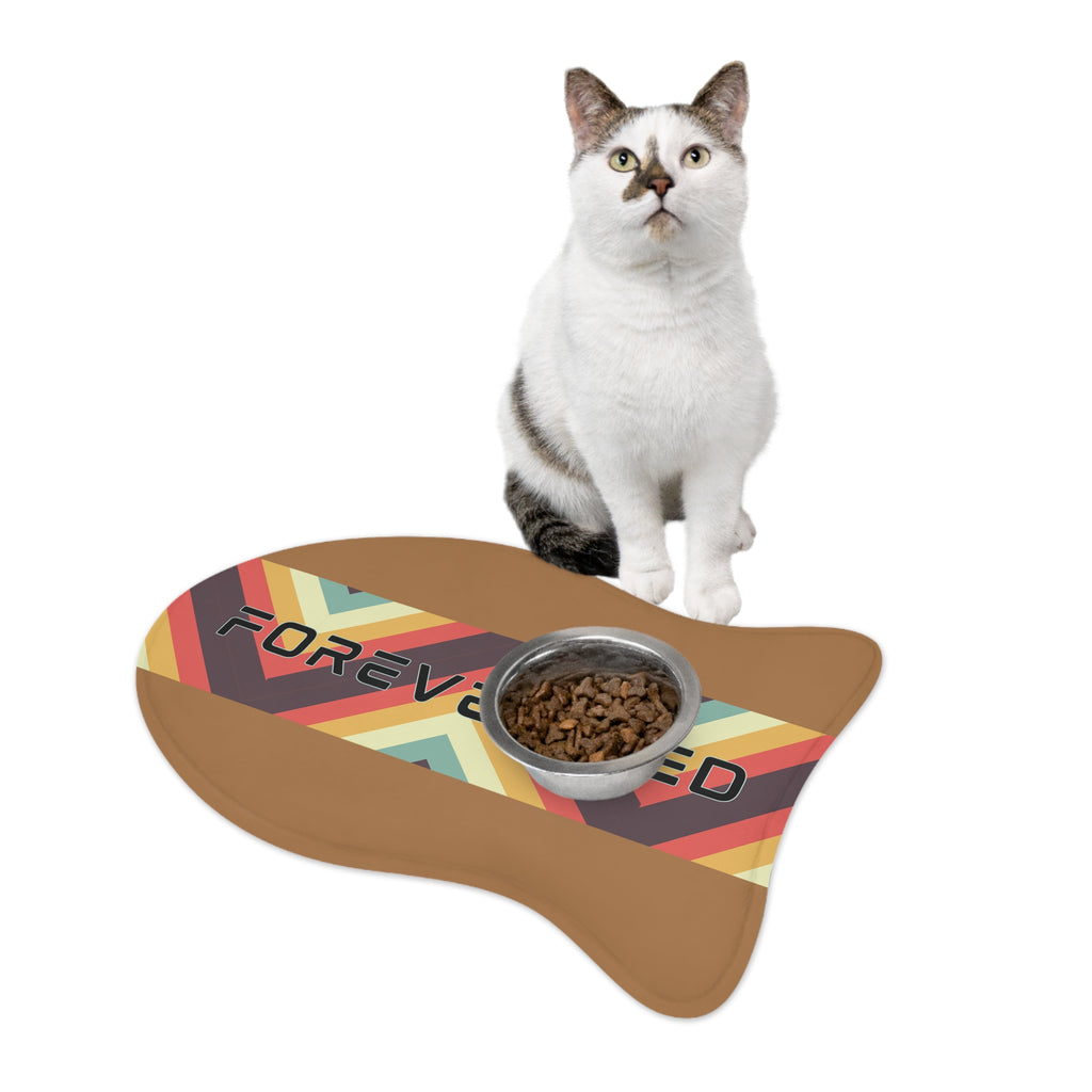 White and gray cat sitting next to “Forever Fed” retro-style pet feeding mat with food bowl.