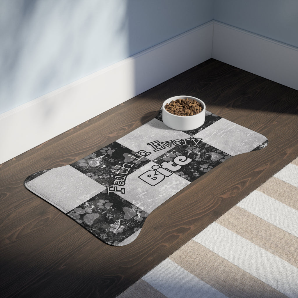 Bone‑shaped plush pet feeding mat in black and white checkerboard paw print design, featuring the phrase “Faith in Every Bite” in a room.