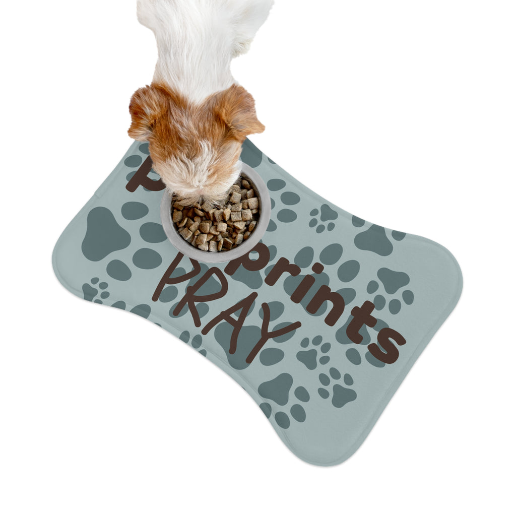 Bone‑shaped plush pet feeding mat with aqua background, dark grey paw print pattern, and brown text “Pawprints Pray”.
