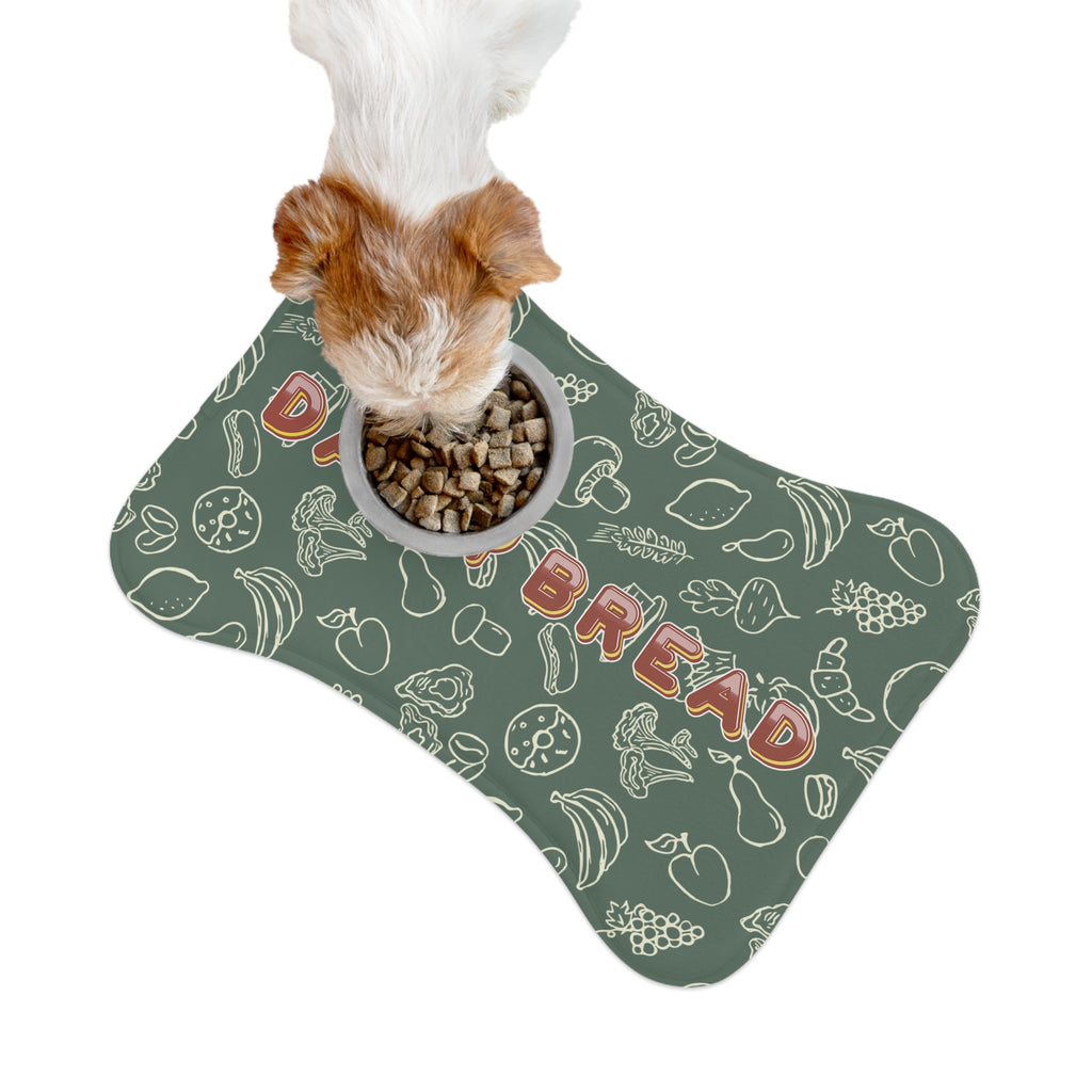 Small dog eating kibble from a bowl placed on sage greenl pet feeding mat with white doodle pattern.