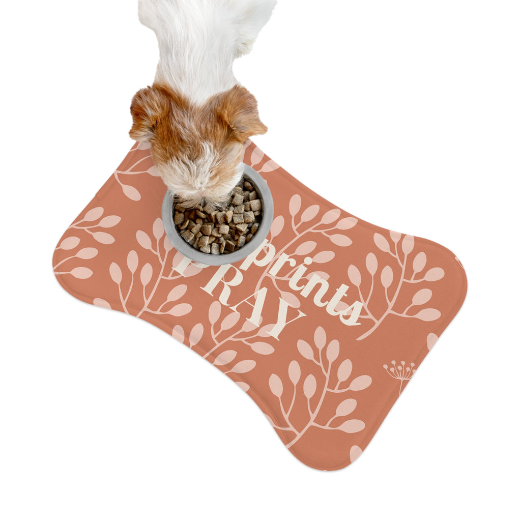 Dog eating kibble from a bowl placed on terracotta botanical feeding mat shaped like a bone.