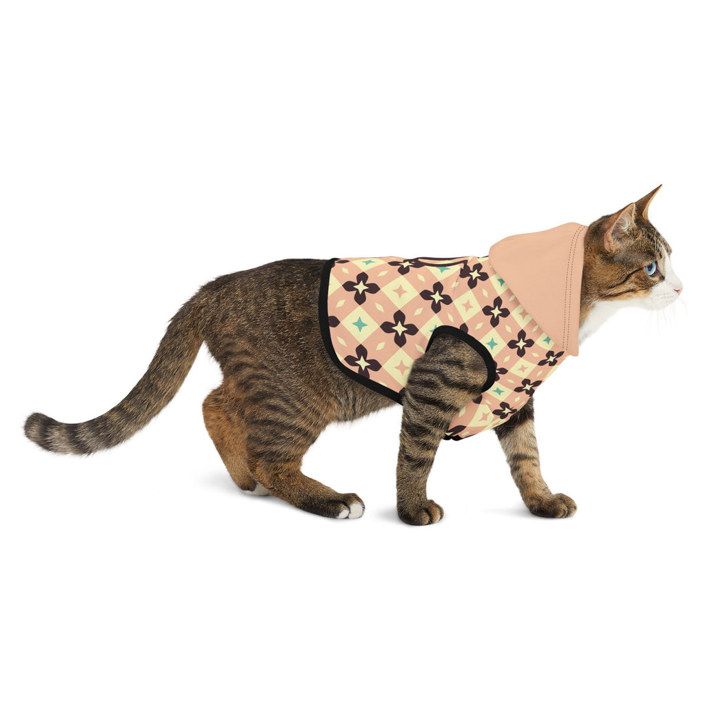 Side view of a brown cat wearing light peach geometric hoodie wearing the green dog hoodie.