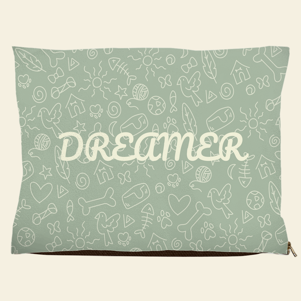 Sage green pet bed with Dreamer text and doodle design of bones, hearts, fish, and birds