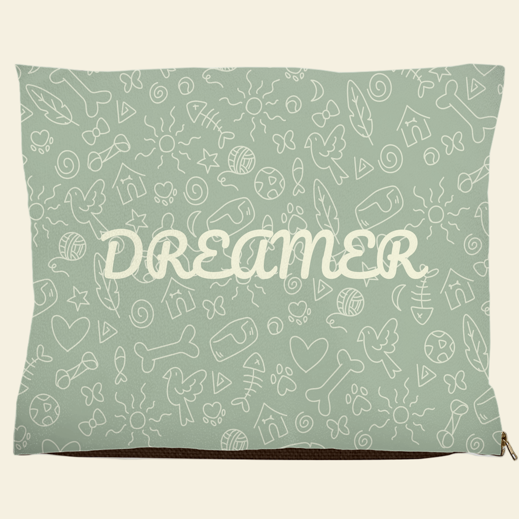 Sage green pet bed with Dreamer text and doodle design of bones, hearts, fish, and birds