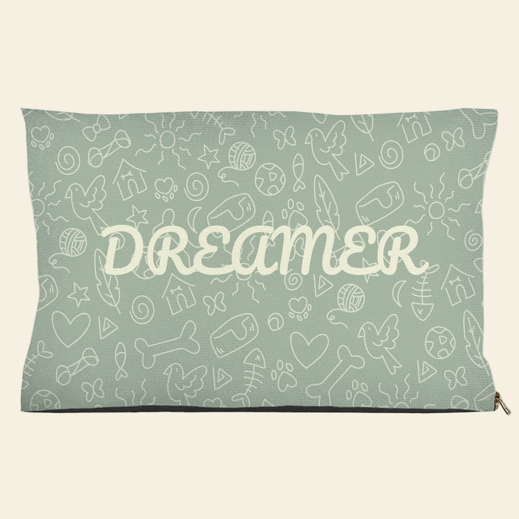 Sage green pet bed with Dreamer text and doodle design of bones, hearts, fish, and birds