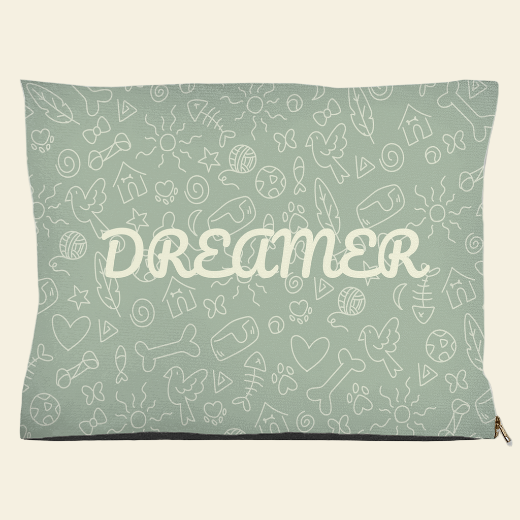 Sage green pet bed with Dreamer text and doodle design of bones, hearts, fish, and birds
