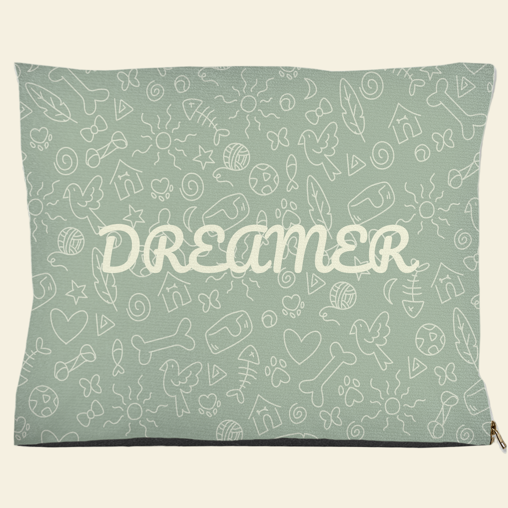 Sage green pet bed with Dreamer text and doodle design of bones, hearts, fish, and birds
