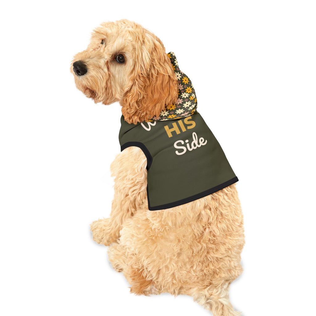 Fluffy light tan dog wearing an olive green dog hoodie, turned to the side to display the graphic, " Walking by HIS Side", on the back with the floral design hood.