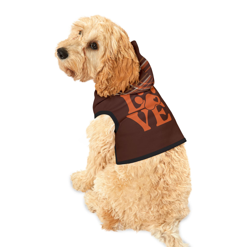 Light-colored dog wearing brown pet hoodie with orange “LOVE” paw print graphic and plaid hood, sitting and looking back.