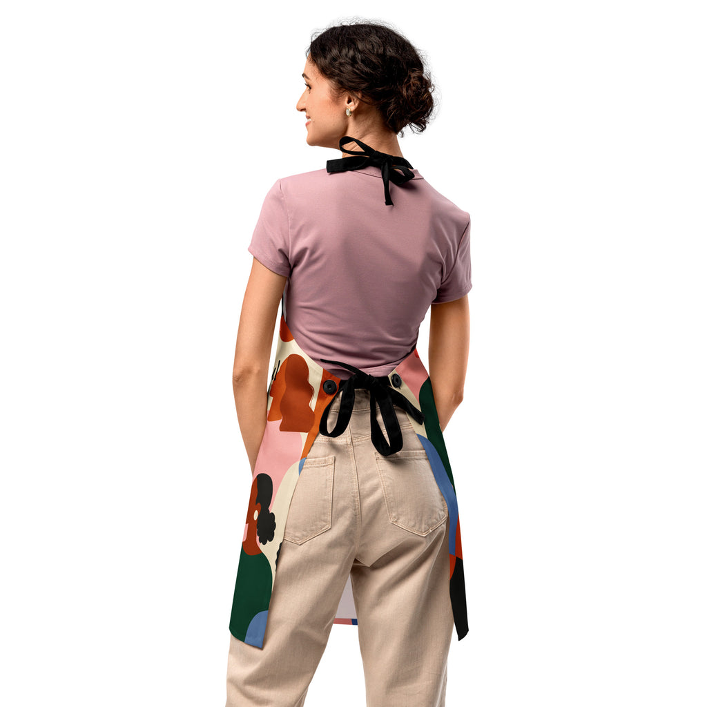 Faith Feeds the Soul apron featuring colorful, abstract silhouettes of diverse people in warm earthy tones — green, terracotta, blush, blue, and cream — with black text that reads “Faith feeds the soul.”