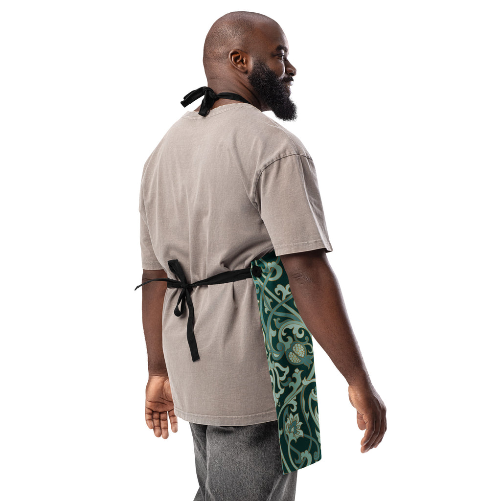 Faith-inspired apron with ornate sage and emerald baroque-style floral pattern, featuring the phrase “God’s Love  One Meal at a Time” in elegant gold lettering across the chest.