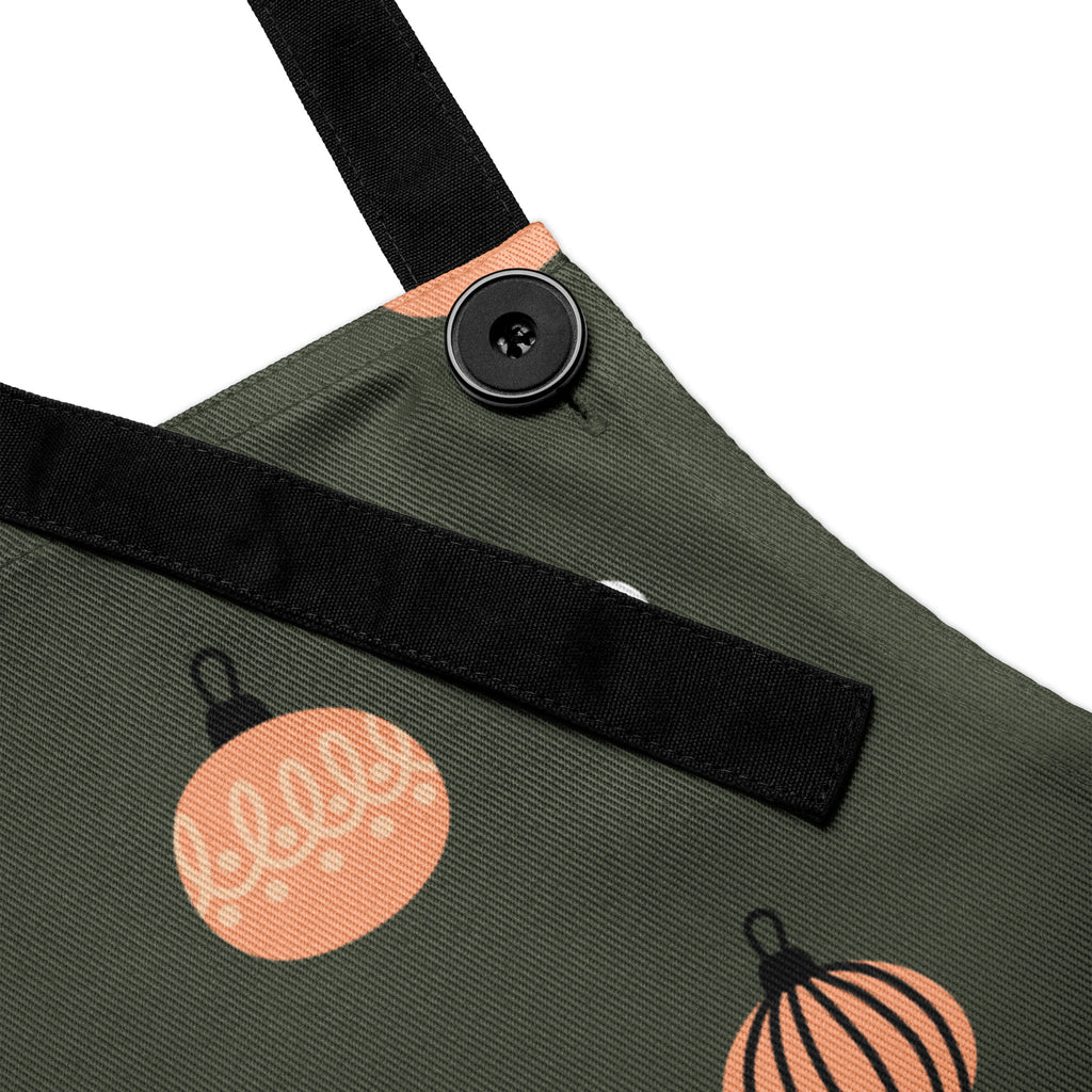 Close up view of apron, designed with Christmas ornaments with the phrase, " Cooking with Grace".