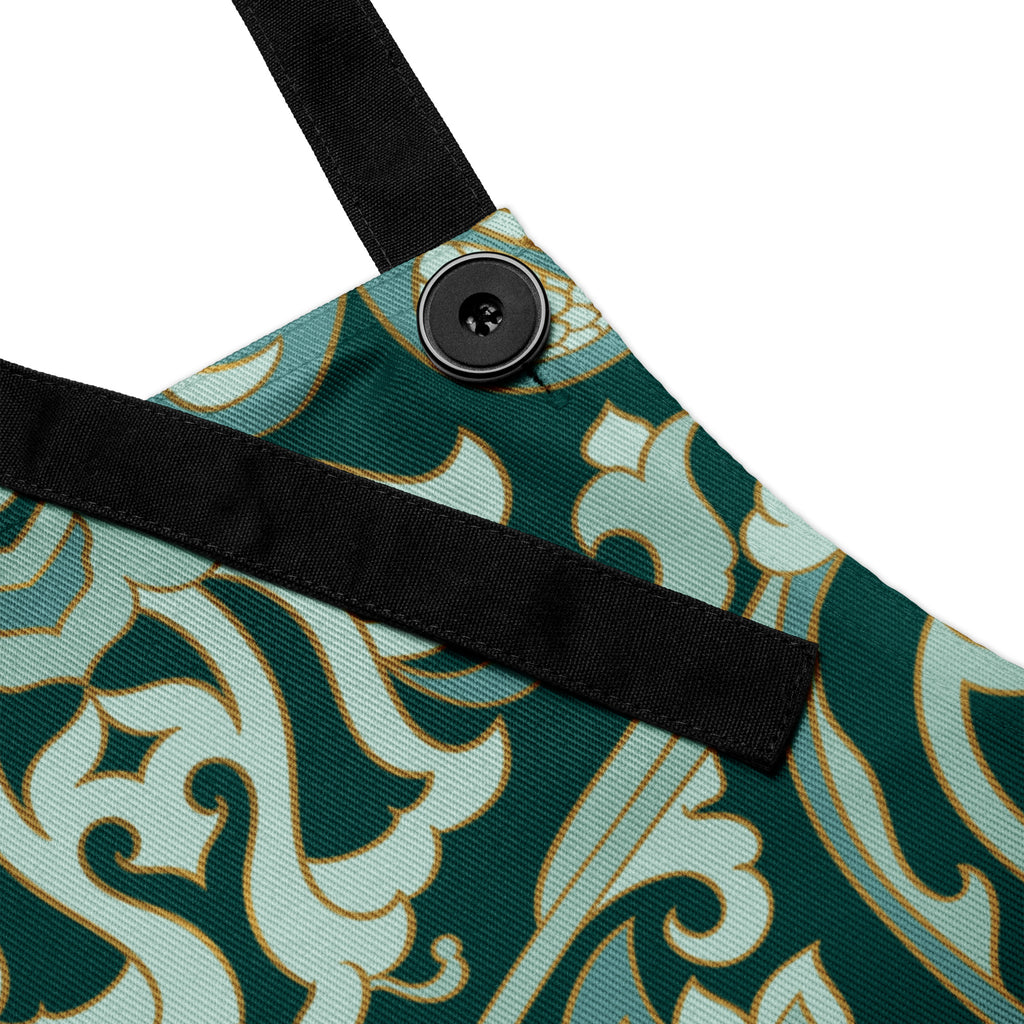 Faith-inspired apron with ornate sage and emerald baroque-style floral pattern, featuring the phrase “God’s Love One Meal at a Time” in elegant gold lettering across the chest.