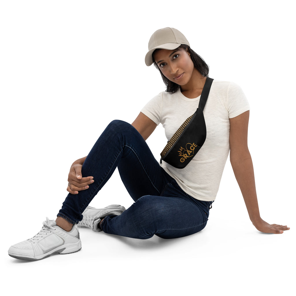 Woman wearing a black GRACE fanny pack with gold crown and heart design, styled crossbody over a white T-shirt and jeans.