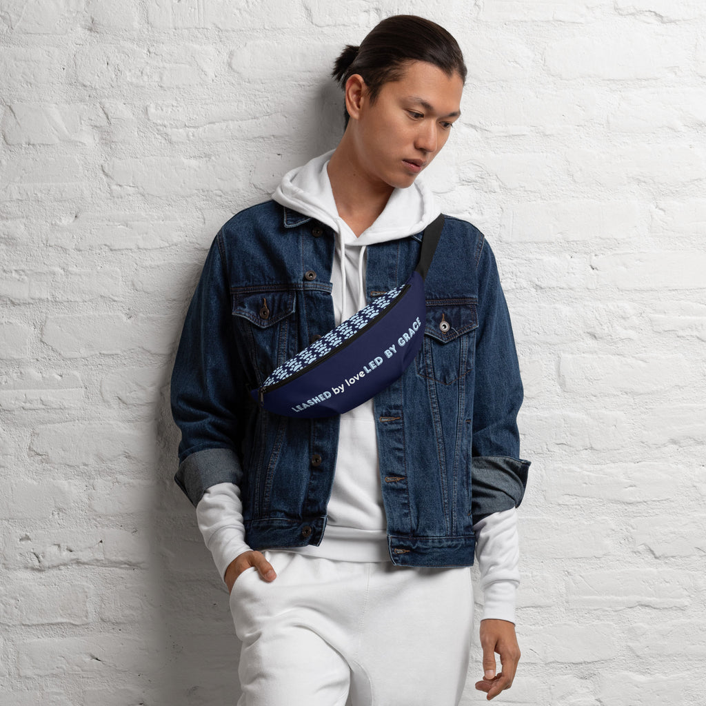 Front view of navy blue fanny pack with the phrase “LEASHED BY LOVE, LED BY GRACE” in light blue letters, decorated with paw prints.