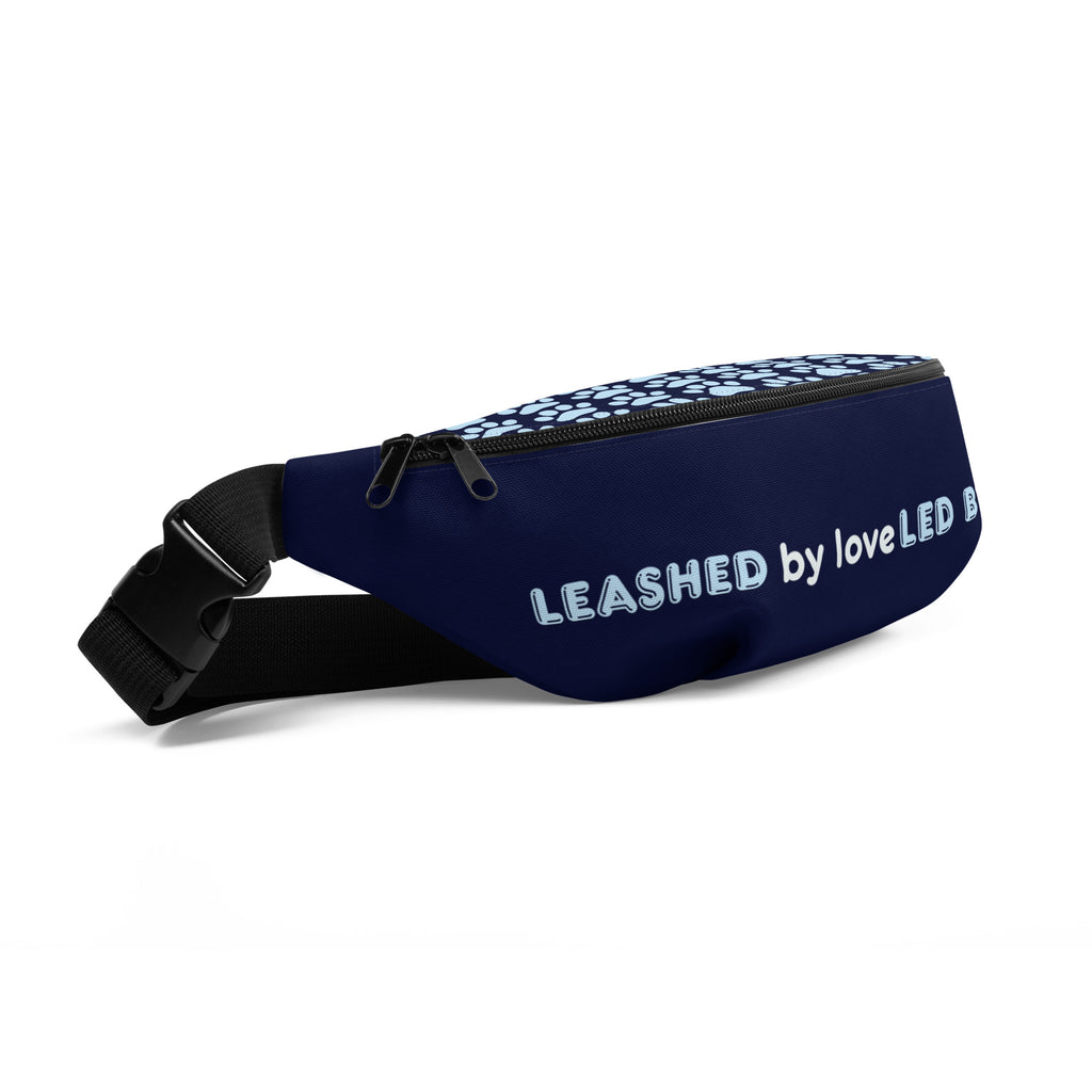 Side view of navy blue fanny pack with the phrase “LEASHED BY LOVE, LED BY GRACE” in light blue letters, decorated with paw prints.
