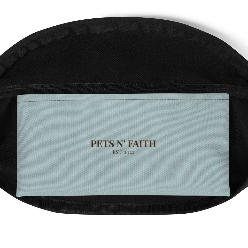 Inside pocket of blue gray  fanny pack with “Pets N’ Faith EST. 2022” label in blue gray and dark brown.