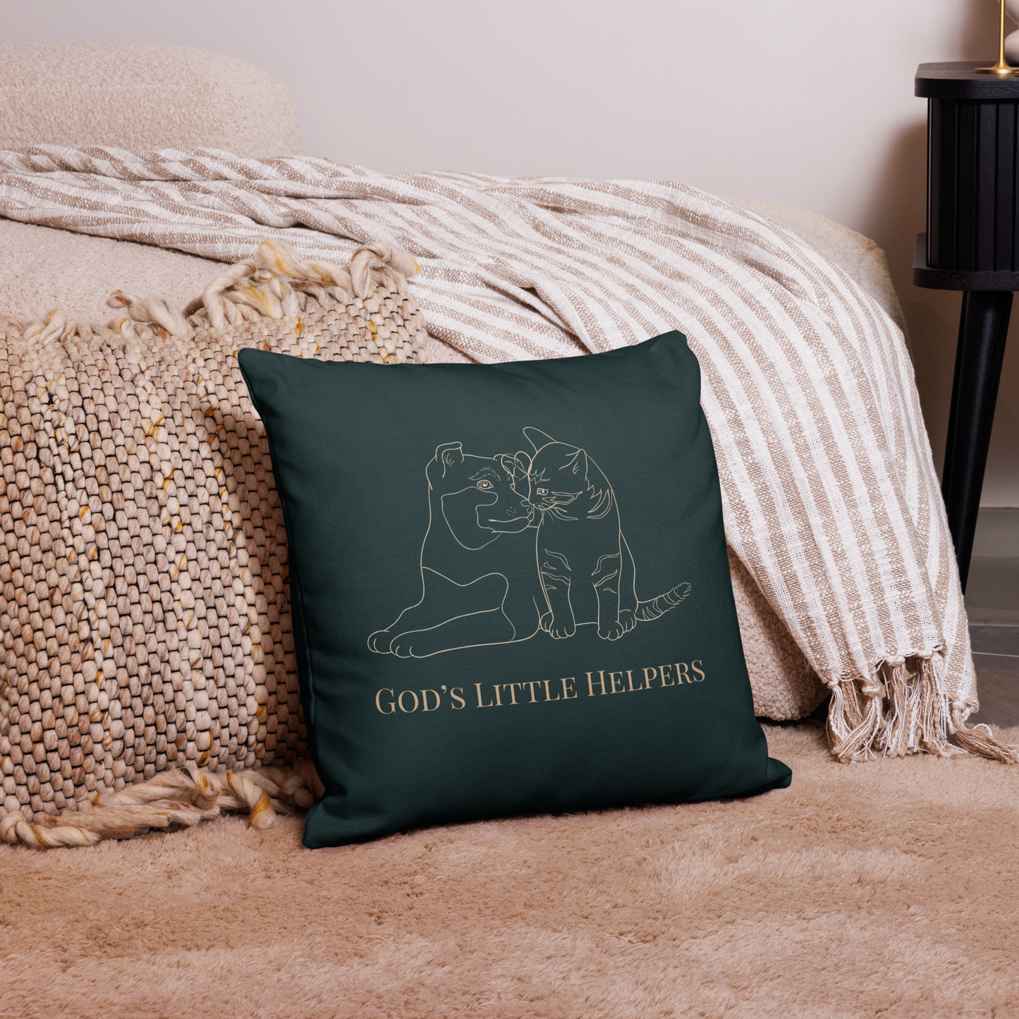 Forest green pillow with cat design and 'God's Little Helpers' text on a beige couch.
