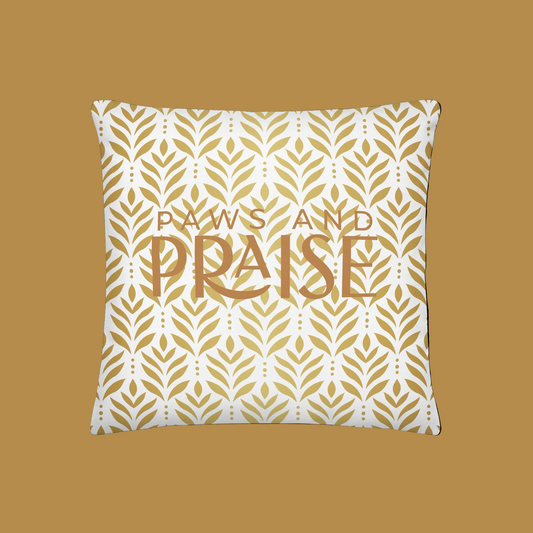 Decorative pillow with gold leaf pattern and 'Paws and Praise' text on a white background