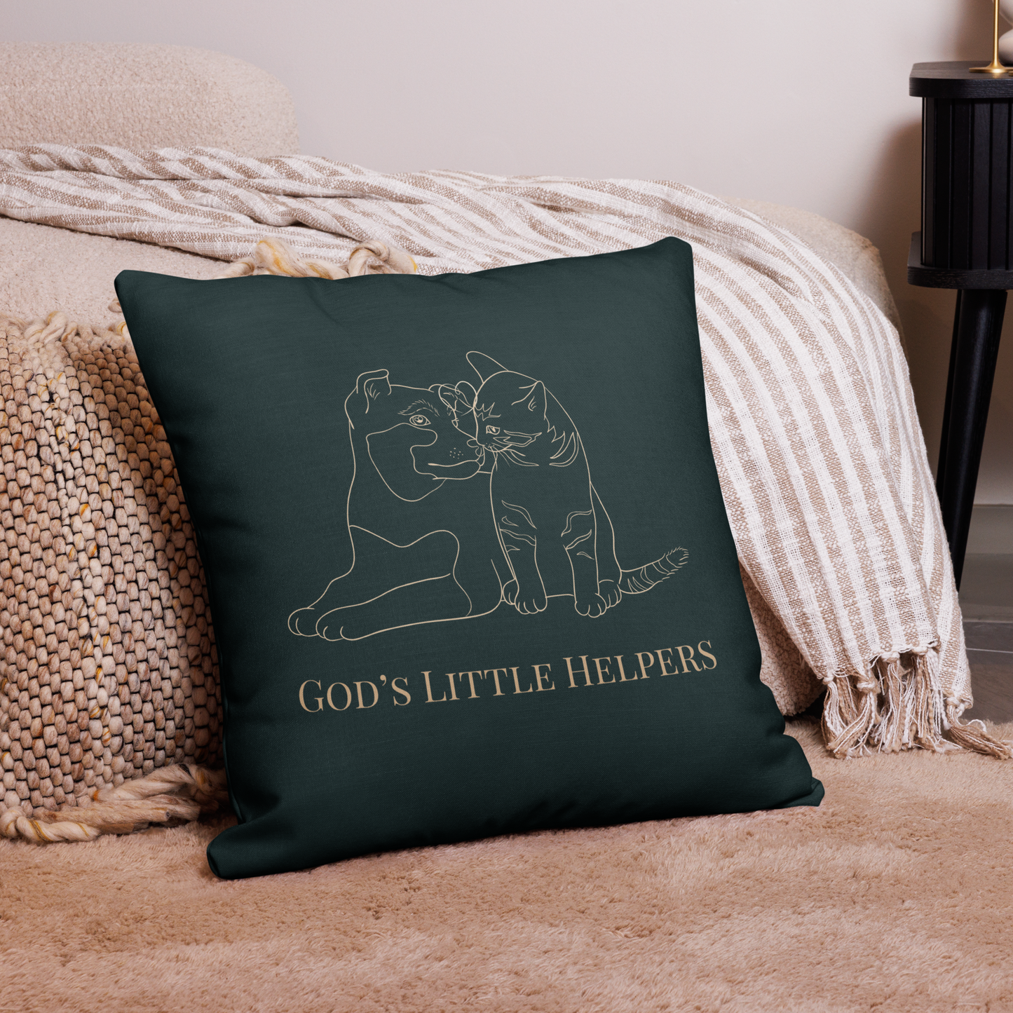 Forest green pillow with cat and dog illustration and 'God's Little Helpers' text on a beige couch.