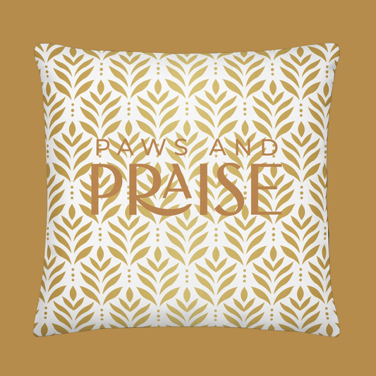 Decorative pillow with gold leaf pattern and 'Paws and Praise' text on a white background