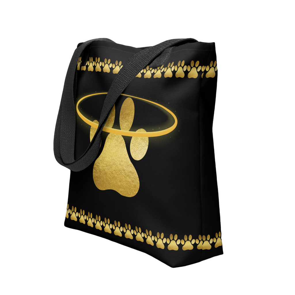 Black tote bag featuring a shimmering gold paw print surrounded by a halo and paw border, designed by Pets N’ Faith.