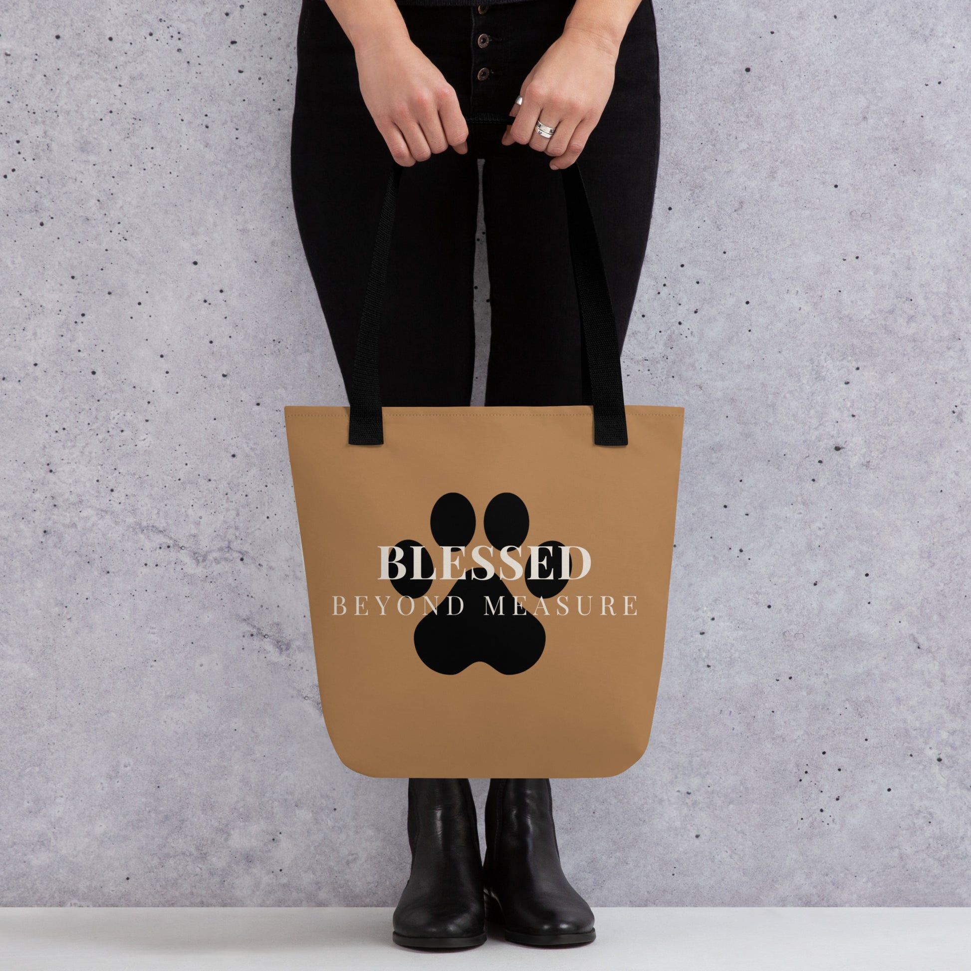 Person holding a brown tote bag with a paw print and text against a gray background