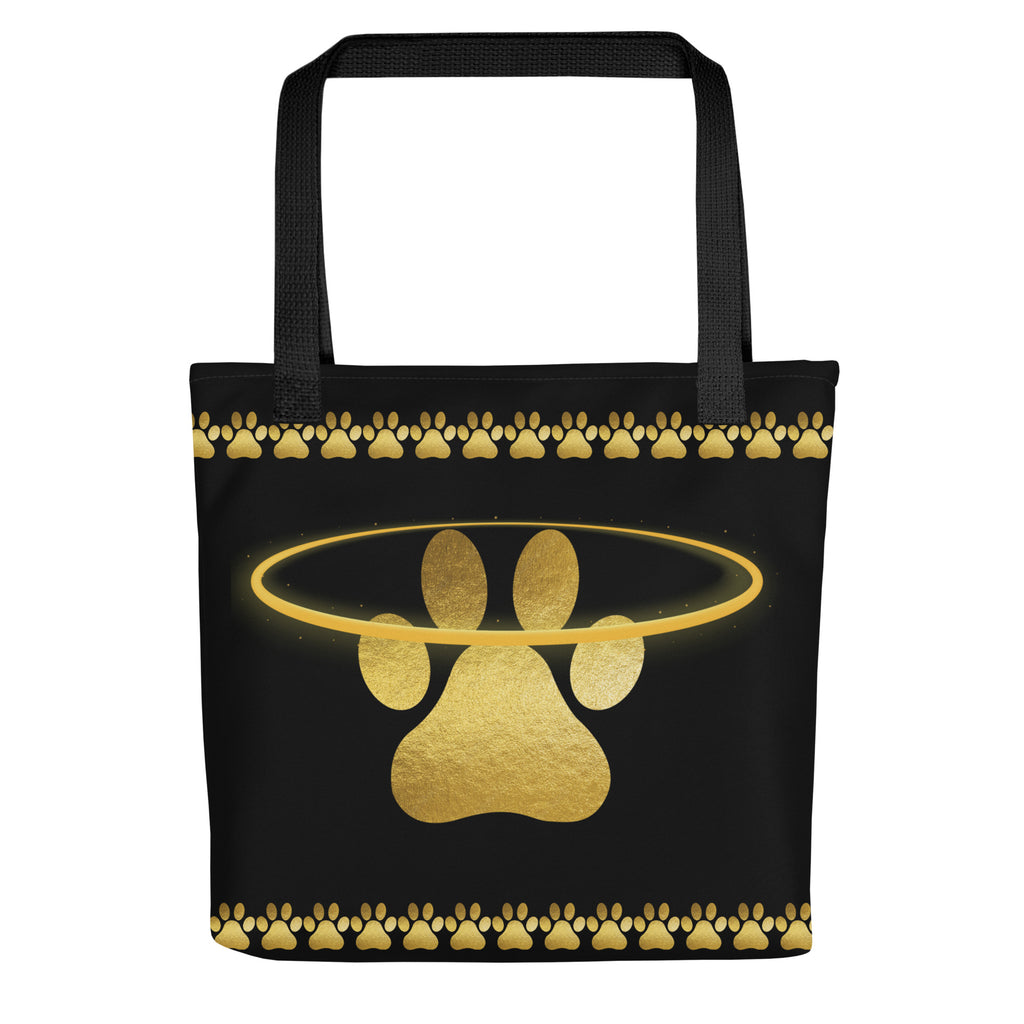 Black tote bag featuring a shimmering gold paw print surrounded by a halo and paw border, designed by Pets N’ Faith.