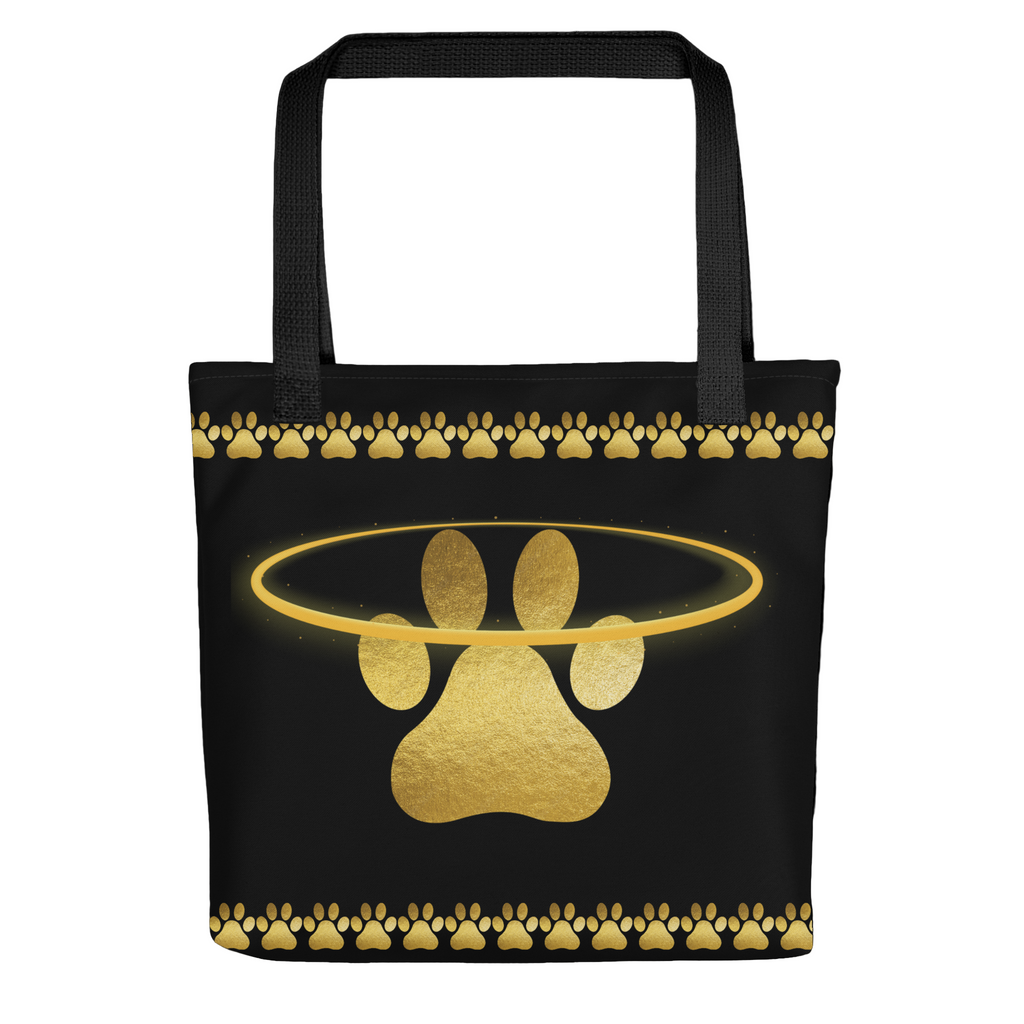 Black tote bag featuring a shimmering gold paw print surrounded by a halo and paw border, designed by Pets N’ Faith.