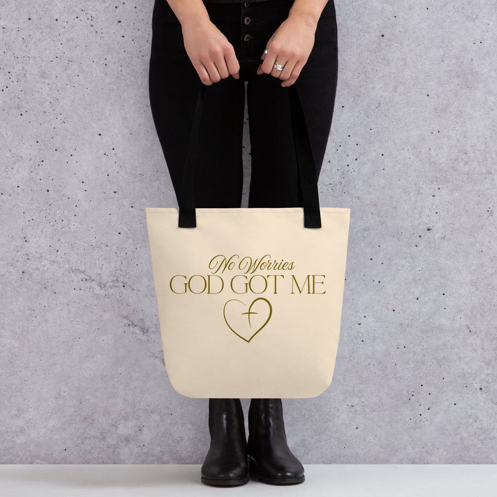 Soft peach tote bag with the words, " No Worries, God Got Me", with a gold heart and cross design.