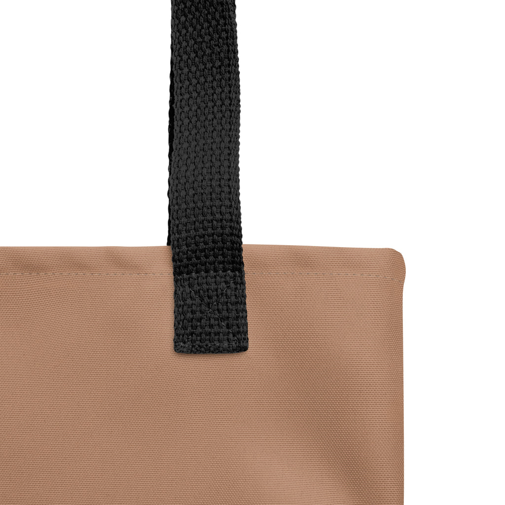 Close-up of black woven strap attached to tan eco tote bag, showing sturdy stitching detail.
