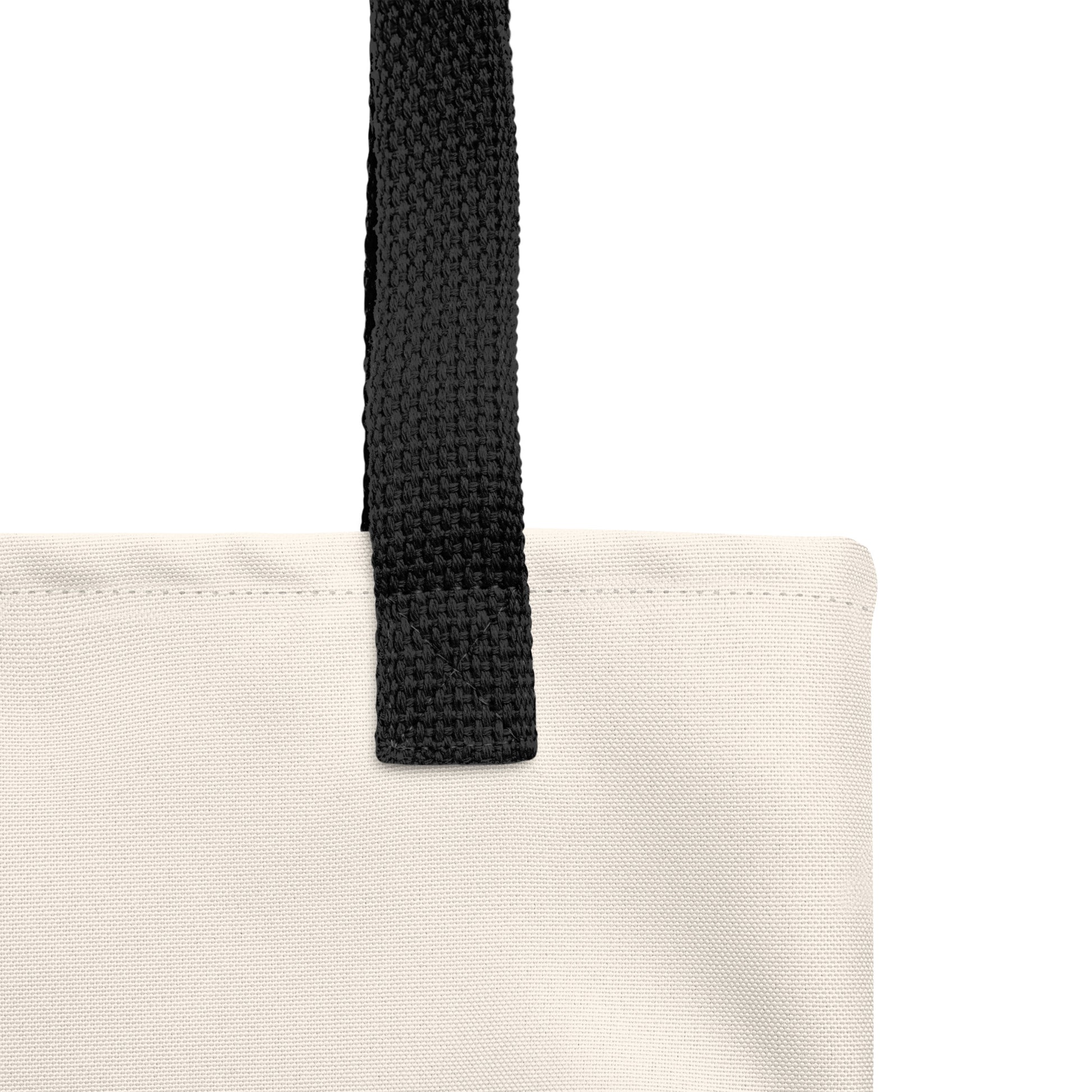Close-up of a beige tote bag with a black strap on a white background