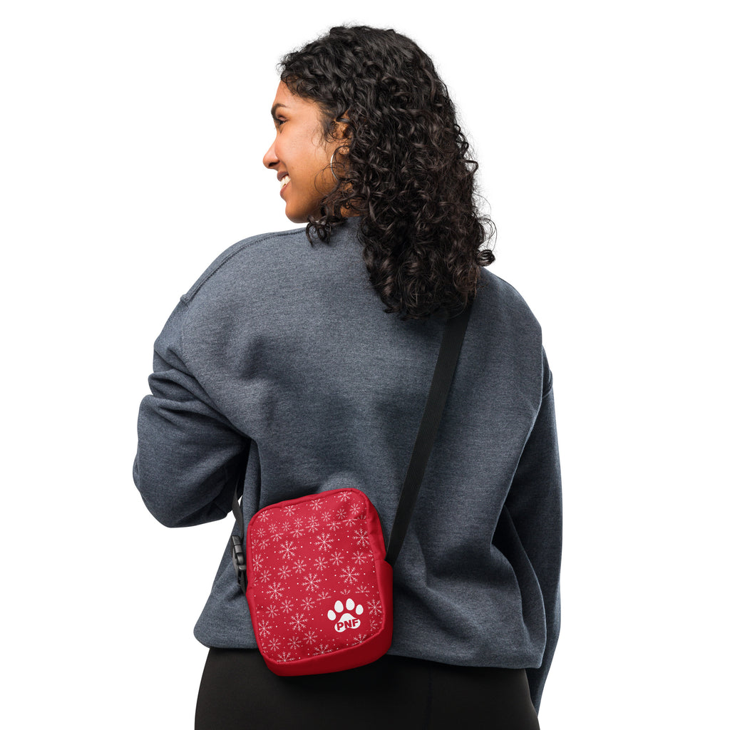 Red crossbody bag featuring a white snowflake pattern, festive holiday design