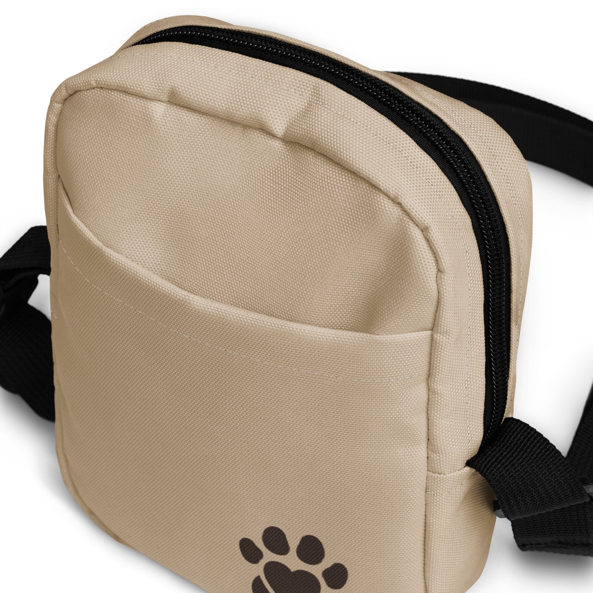 Beige crossbody bag with a brown paw print logo on a white background