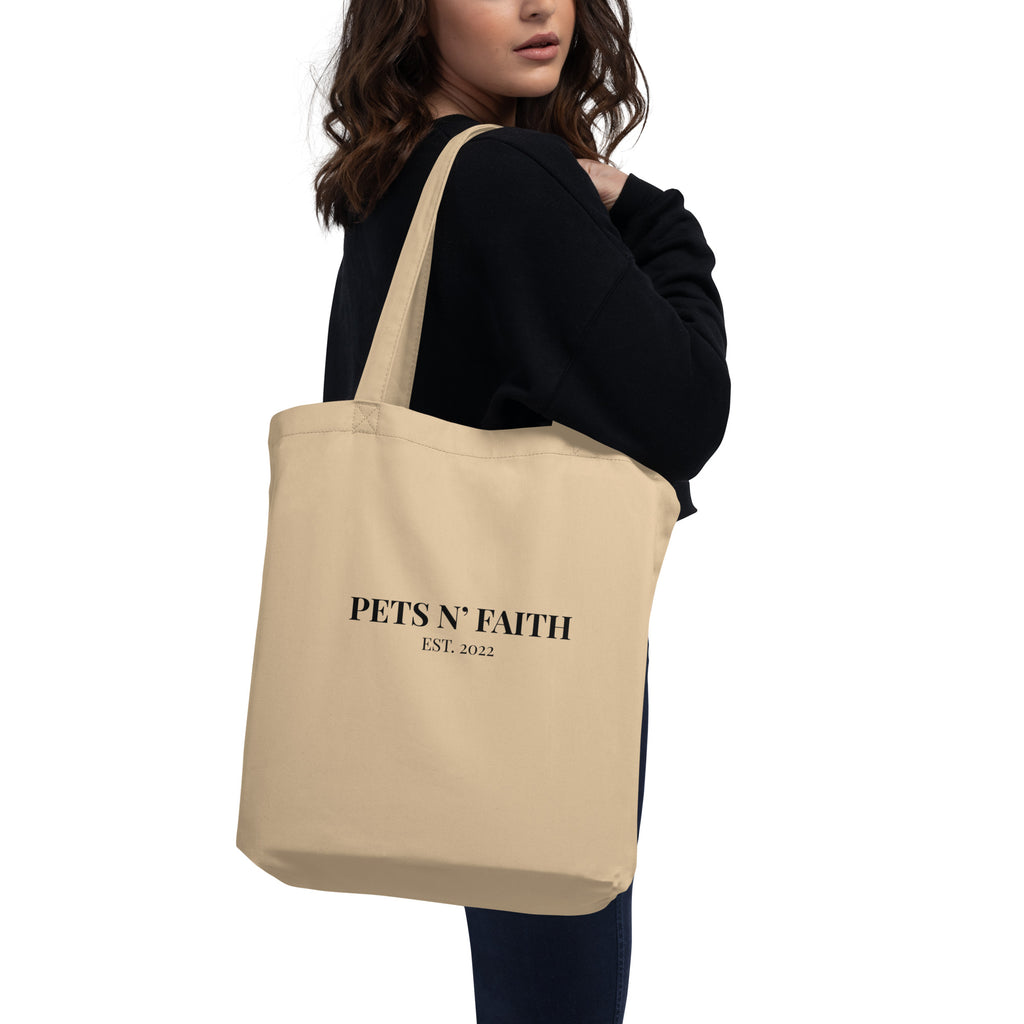 Woman holding beige tote bag with black cat silhouette and Job 12:7 scripture design.