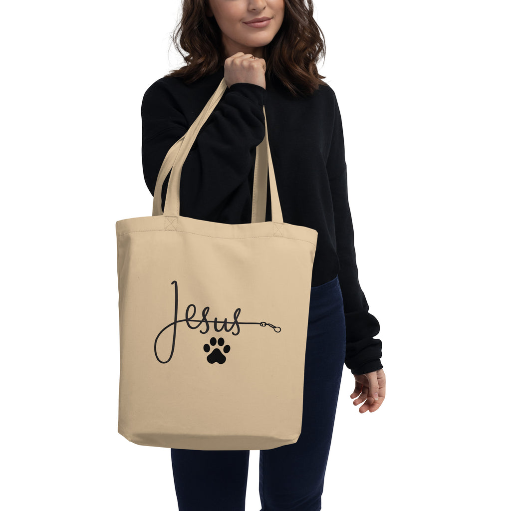 Beige organic cotton tote bag with the word ‘Jesus’ written in cursive connected to a black paw print, symbolizing faith and love for pets – by Pets N’ Faith