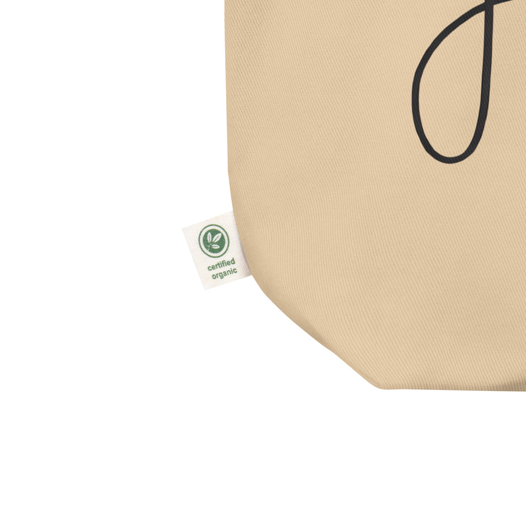 Close up of Beige organic cotton tote bag with the word ‘Jesus’ written in cursive connected to a black paw print, symbolizing faith and love for pets – by Pets N’ Faith
