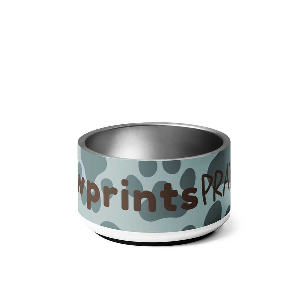 Stainless steel pet bowl with soft blue background and scattered dark paw prints, featuring the text “Pawprints Pray” in brown bold and handwritten font.
