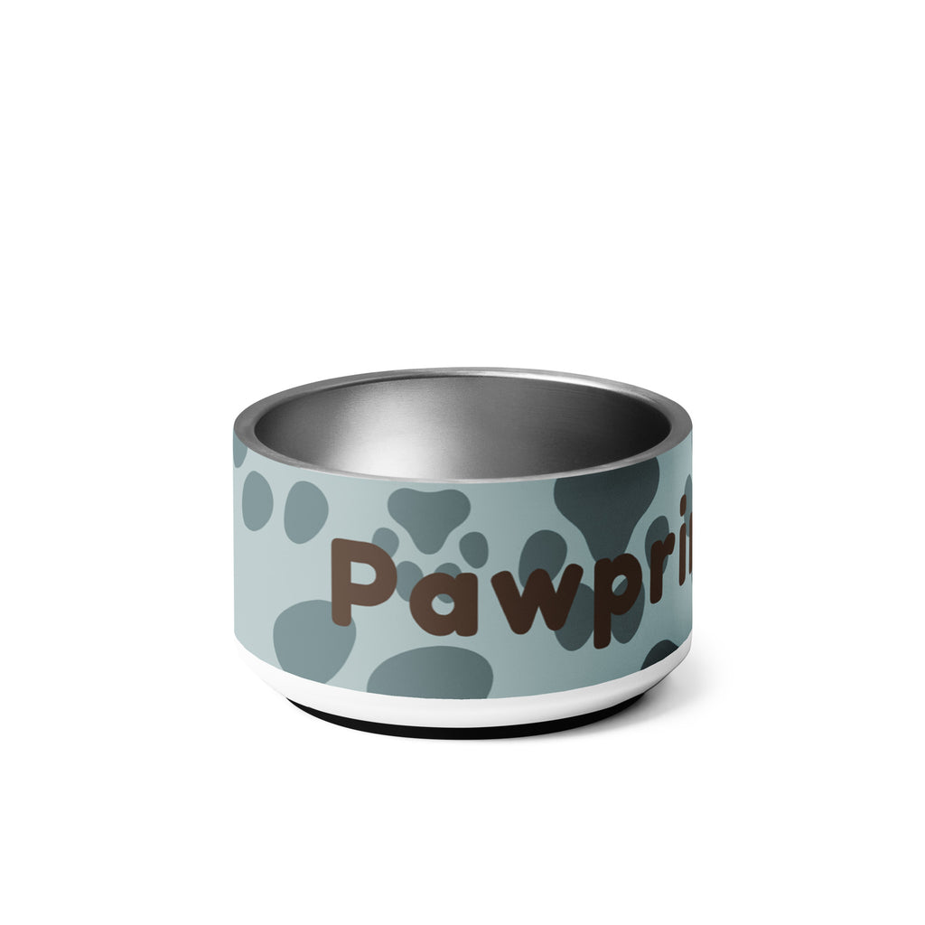 Side view of stainless steel pet bowl with soft blue background and scattered dark paw prints, featuring the text “Pawprints Pray” in brown bold and handwritten font.
