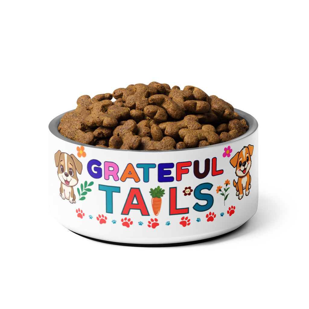 “Grateful Tails” stainless steel pet bowl full of brown, bone-shaped kibble on white background.