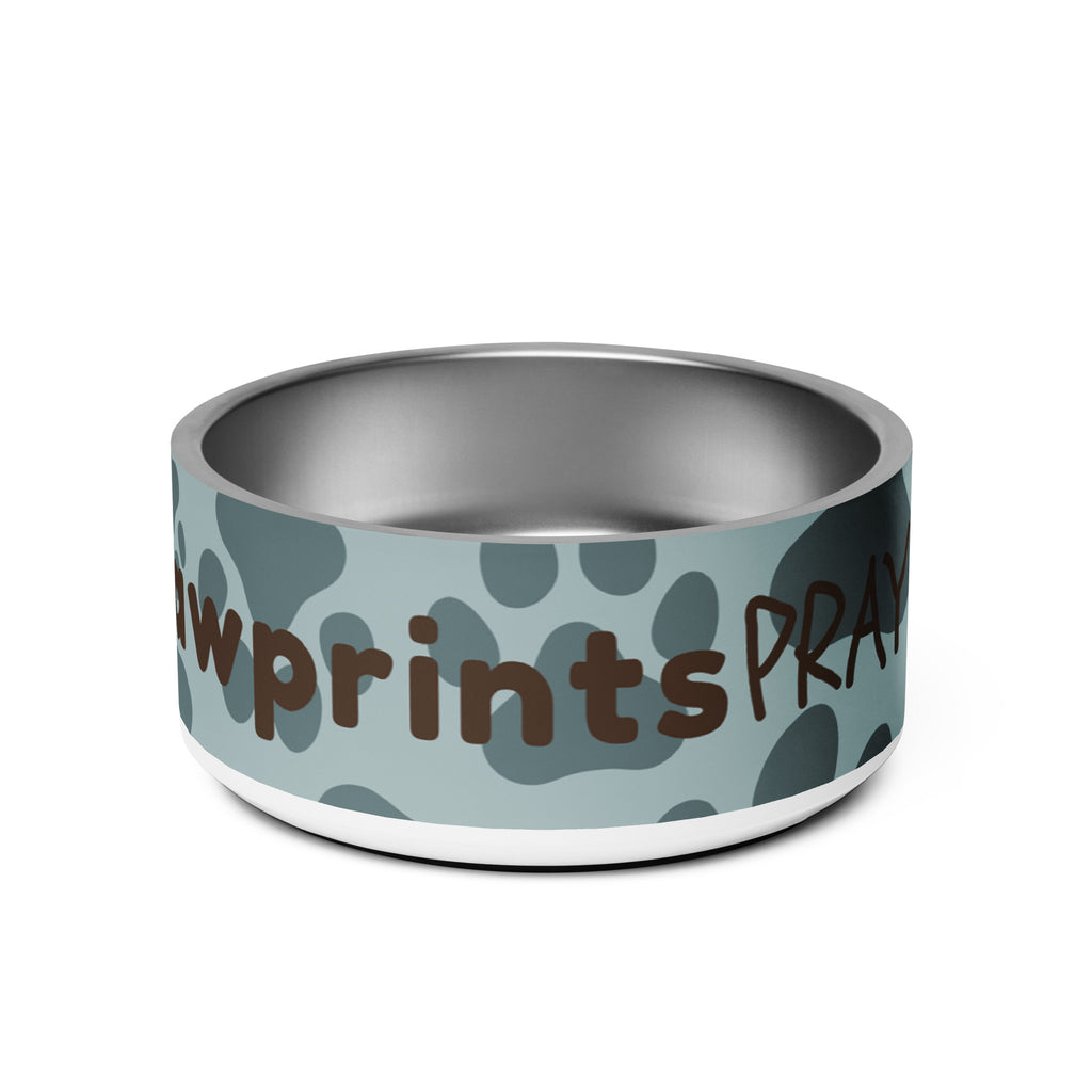 Stainless steel pet bowl with soft blue background and scattered dark paw prints, featuring the text “Pawprints Pray” in brown bold and handwritten font.